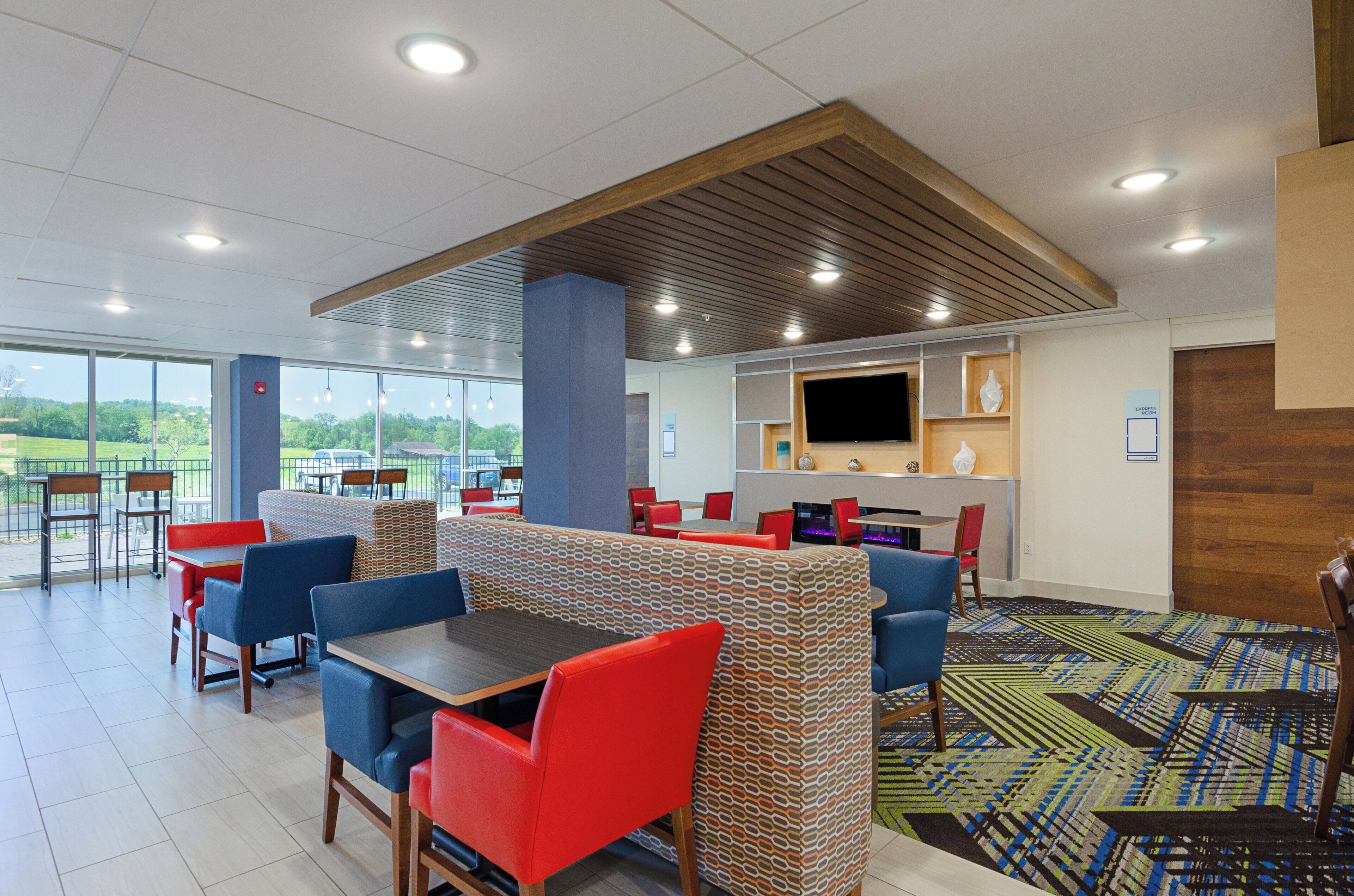 A modern dining area with booths and tables, a flat-screen TV, and a view of the outdoors.