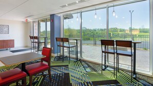 A modern indoor space with a large window, a dining table, and several chairs. - Holiday Inn Express & Suites Abingdon by IHG (Abingdon)