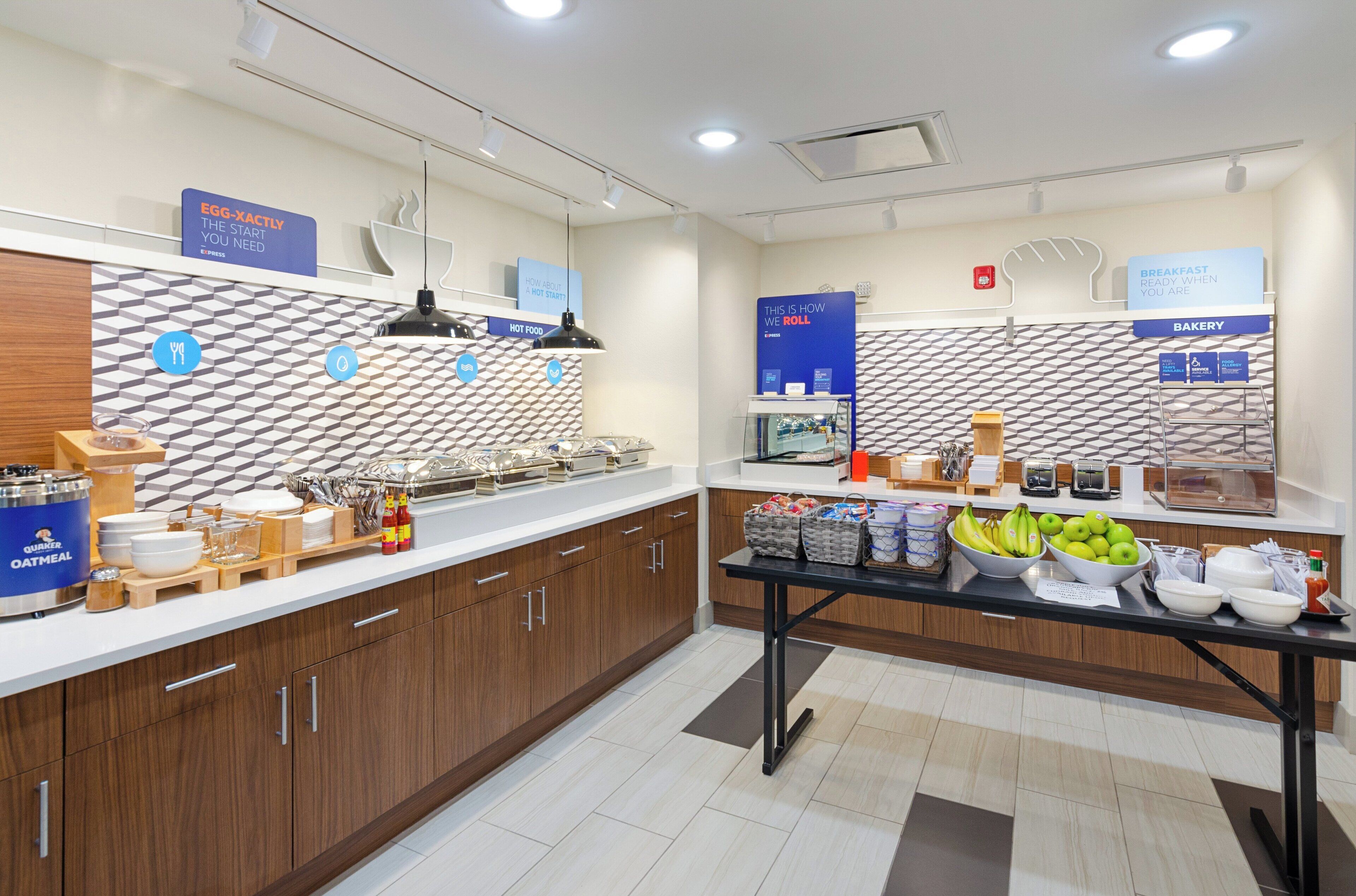 A modern breakfast area with a counter displaying food items and a sign indicating the bakery section.