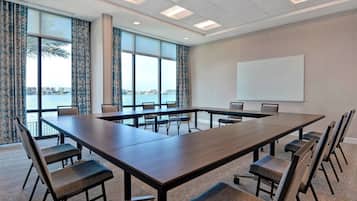 A conference room with a large table and chairs, large windows with curtains, and a whiteboard on the wall.