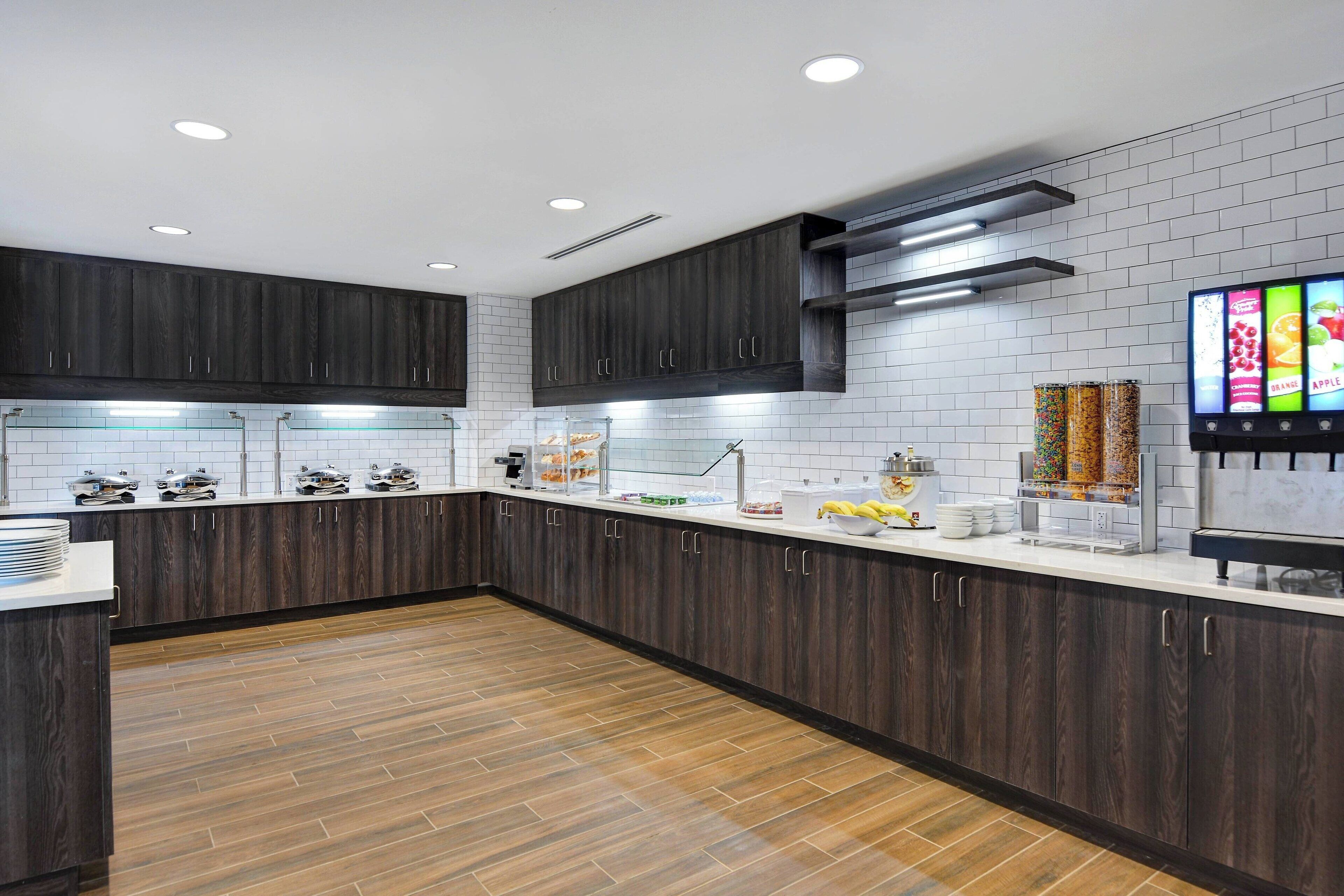 A modern kitchen with dark wood cabinets, white subway tiles, and a wooden floor.