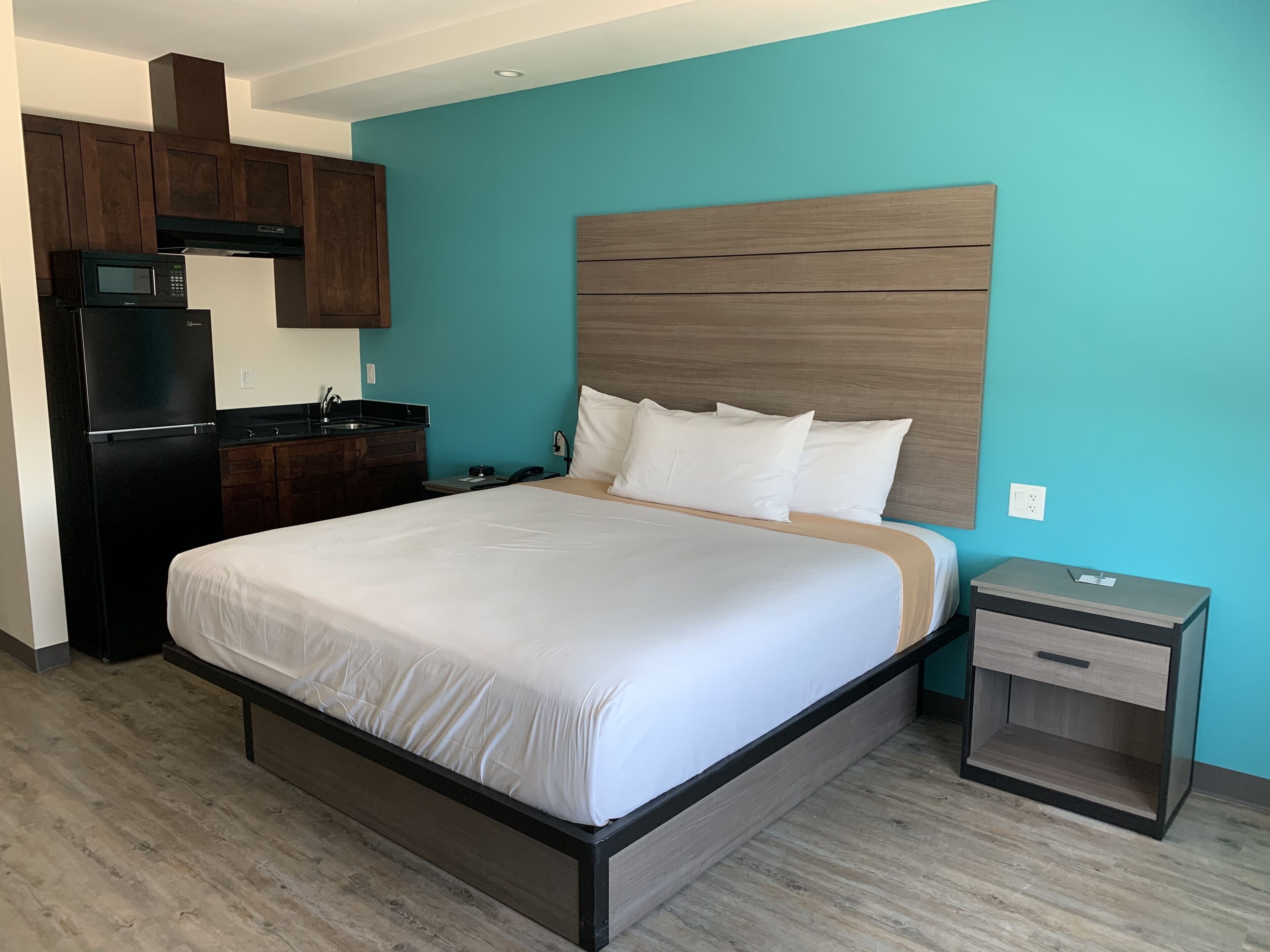 Une chambre d’hôtel équipée d’un lit, d’une table de chevet, d’un petit bureau, d’un four à micro-ondes et d’un réfrigérateur.
