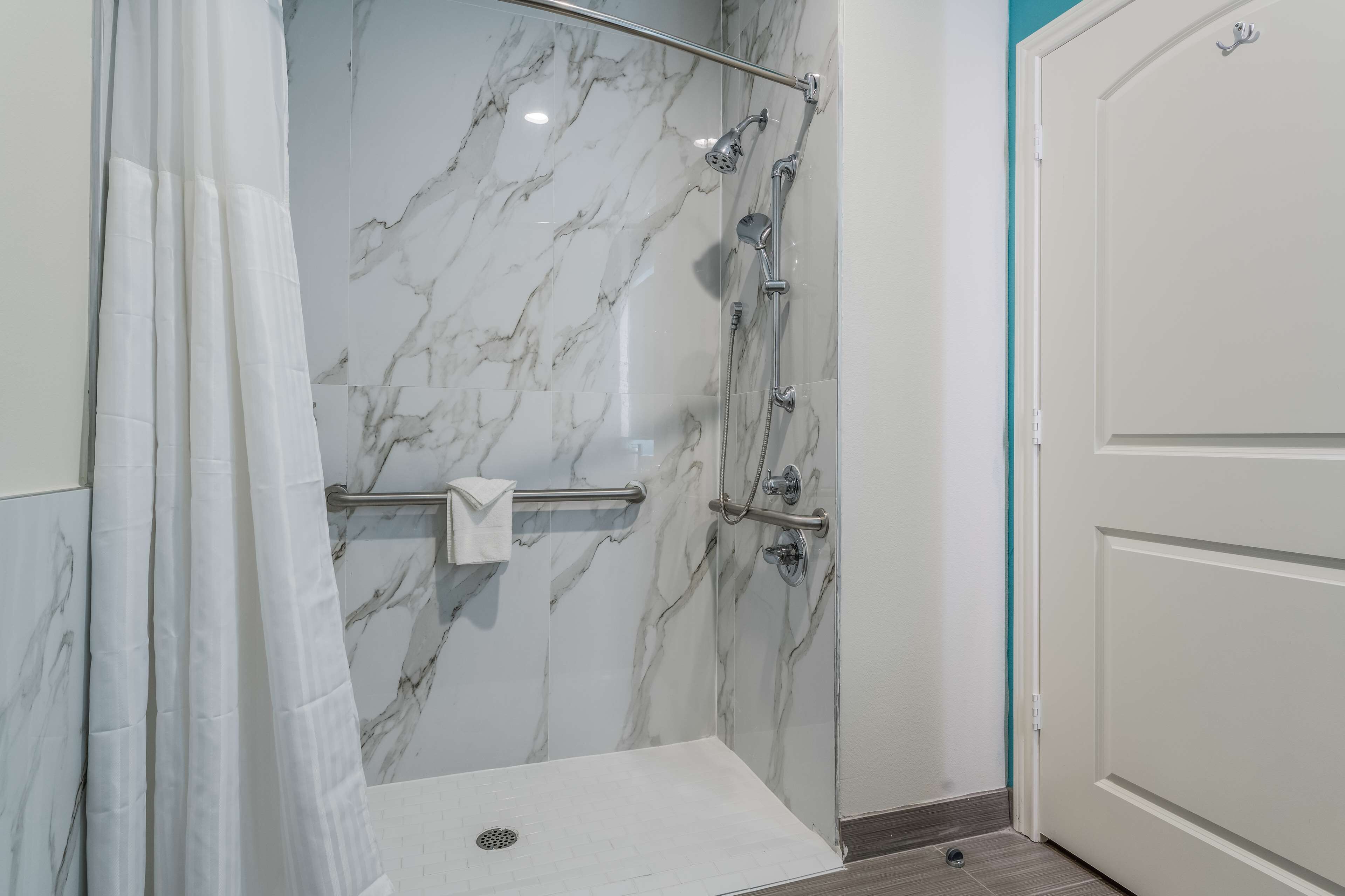 A shower with a glass door, a towel rack, and a marble wall.