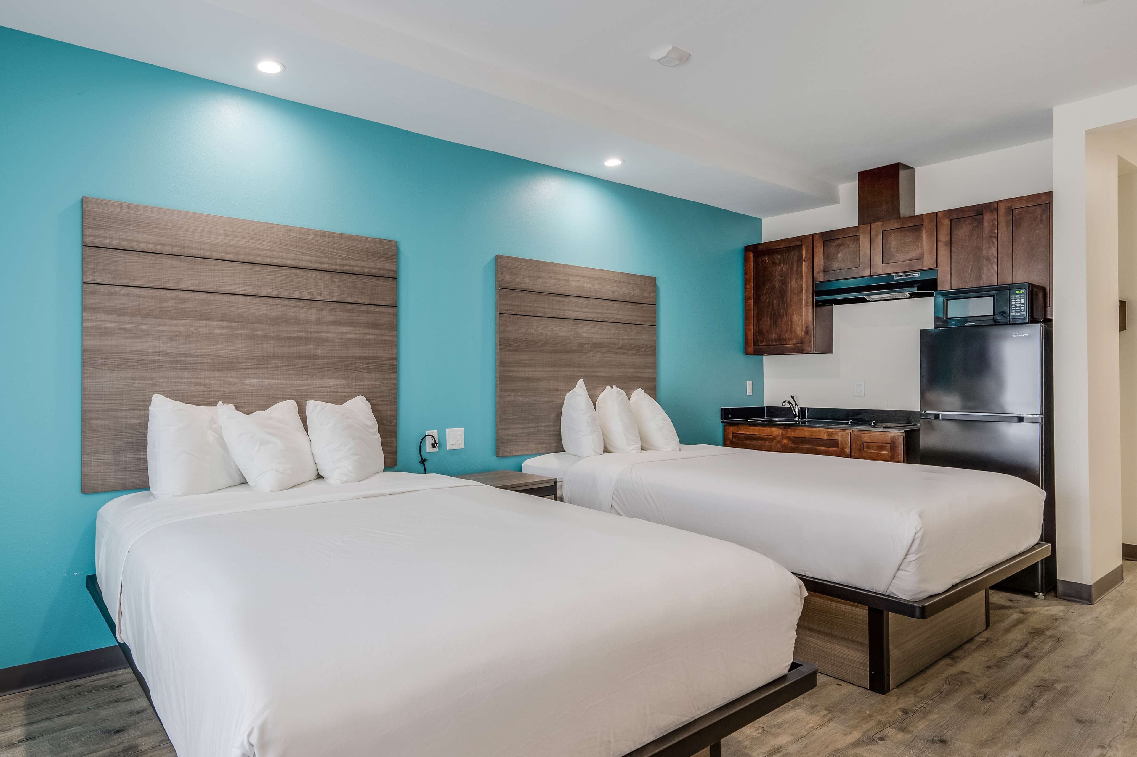 Une chambre d’hôtel avec deux lits, une kitchenette et un mur d’accent bleu.
