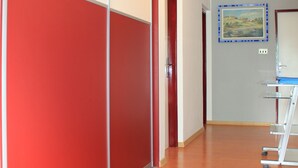 Um corredor com parede vermelha e branca, chão de madeira, uma porta e um quadro na parede.