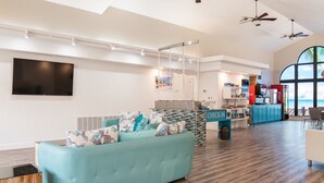 A spacious living area with a teal sofa, a check-in counter, and a large window offering a view of the ocean.