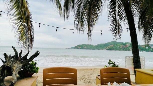 A wooden table with chairs and a view of the sea. - Walking Distance to Playa la Ropa  (Zihuatanejo)