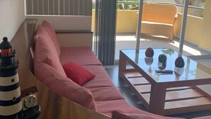A modern living room with a sofa, a glass coffee table, and a view of a tropical landscape. - Walking Distance to Playa la Ropa  (Zihuatanejo)