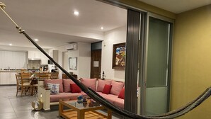 A living room with a sofa, coffee table, and a hammock. - Walking Distance to Playa la Ropa  (Zihuatanejo)