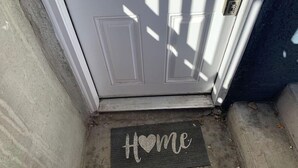 A door with a doormat that reads "Home." - DIA HideAway -2BR, 15 min from DIA DT, Anschutz MD (Commerce City)