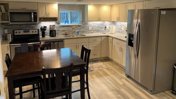 A modern kitchen with a central island, stainless steel appliances, and light wood flooring. - DIA HideAway -2BR, 15 min from DIA DT, Anschutz MD (Commerce City)