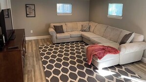 A living room with a sectional sofa, a patterned rug, and two windows. - DIA HideAway -2BR, 15 min from DIA DT, Anschutz MD (Commerce City)