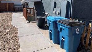 A residential area with a house, a wooden fence, and two blue recycling bins. - DIA HideAway -2BR, 15 min from DIA DT, Anschutz MD (Commerce City)