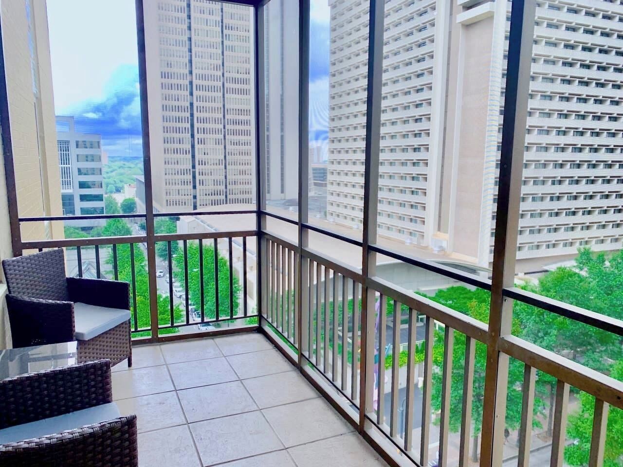 Uma varanda com vista para edifícios e vegetação ao redor.