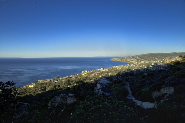 A coastal town with a view of the sea, houses on a hillside, and a clear sky.
