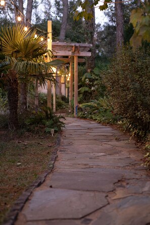 A stone pathway leading to a wooden pergola with string lights. - Sailors Rest: Pool & Sauna, Tropical Island Oasis, Fireplace (Johns Island)