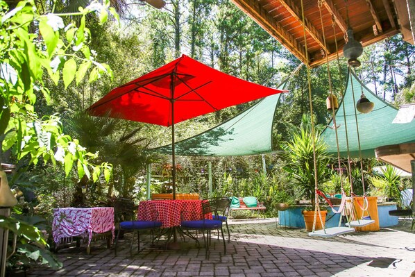 An outdoor patio with tables and chairs, covered by a red umbrella and a green canopy. - Sailors Rest: Pool & Sauna, Tropical Island Oasis, Fireplace (Johns Island)