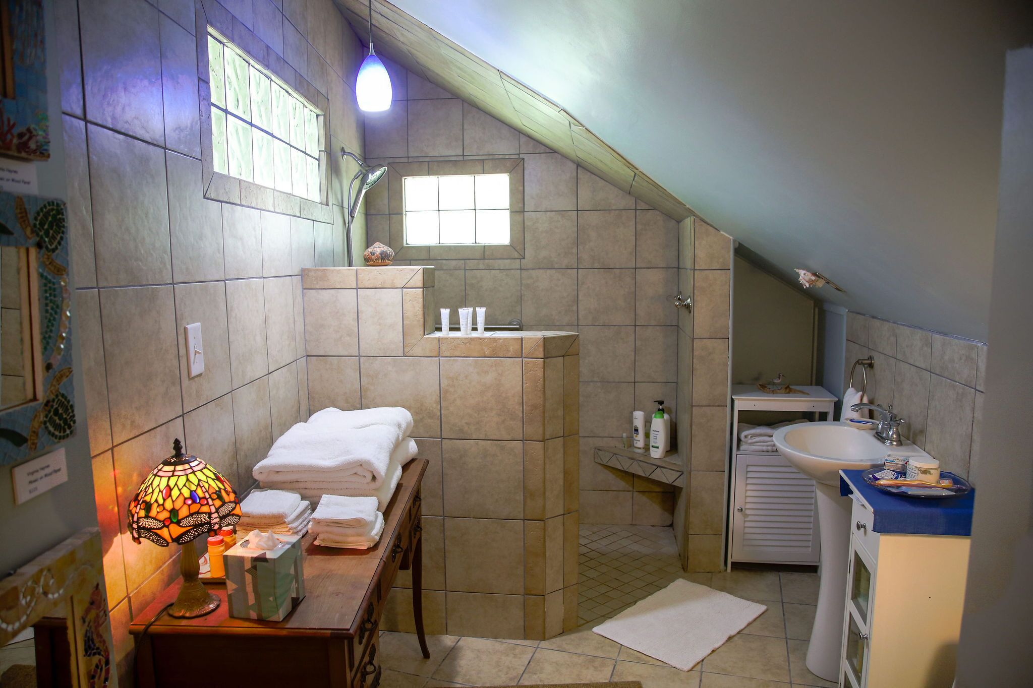 A bathroom with a shower, sink, and a decorative lamp.