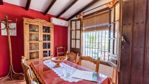 A dining area with a wooden table, chairs, a glass cabinet, and a window with blinds. - El Ranchito de Martín Álora by Ruralidays (Málaga)