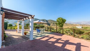 An outdoor patio with a pergola, seating area, and a view of the countryside. - El Ranchito de Martín Álora by Ruralidays (Málaga)
