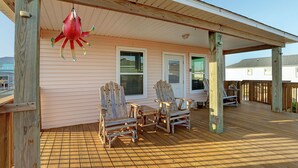 Eine Holzterrasse mit zwei Adirondack-Stühlen und einer hängenden Dekoration.