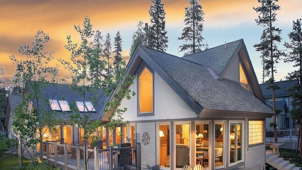 Une maison moderne dotée d’une grande terrasse, d’une cheminée et d’un patio couvert.
