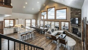 A spacious loft-style living area with a kitchen, dining space, and a fireplace. - Luxury lakeview cabin w/hot tub, pool, sports courts, pickleball, private beach! (Fish Haven)