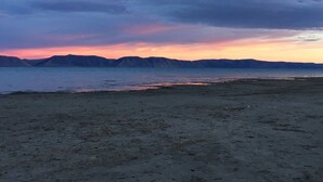 A beach with a view of distant mountains and a sunset sky. - Luxury lakeview cabin w/hot tub, pool, sports courts, pickleball, private beach! (Fish Haven)