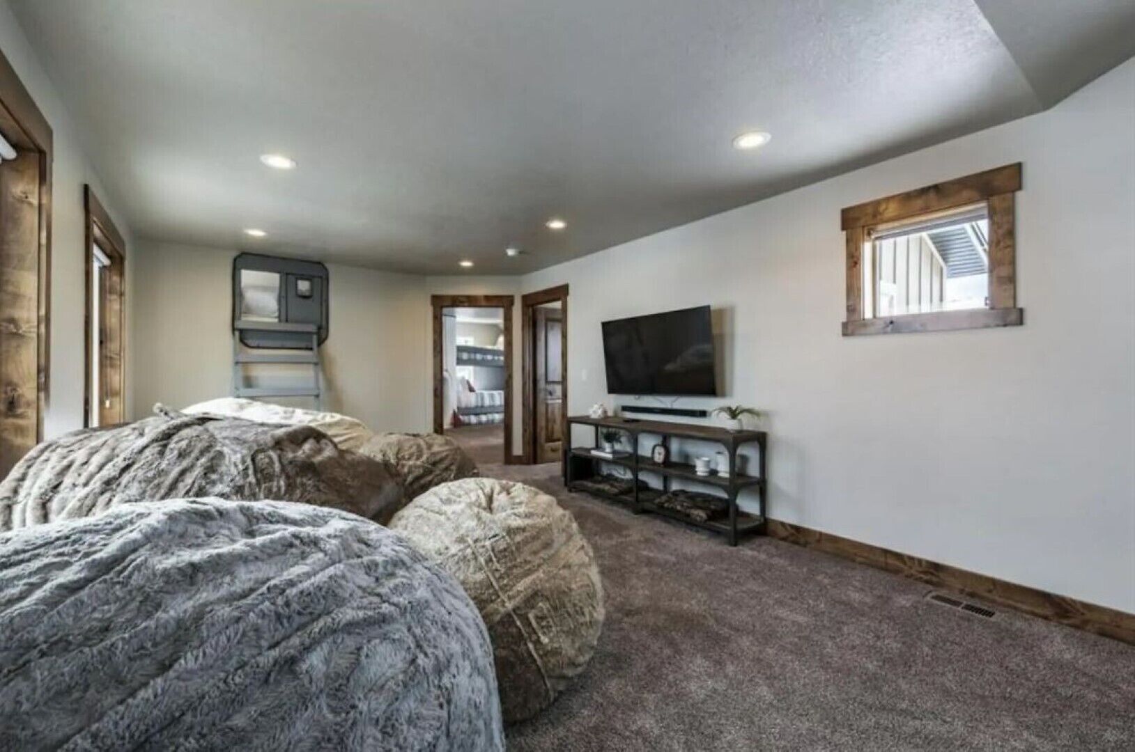 A bedroom with a large bed, a TV on a wooden stand, and a door leading to another room.