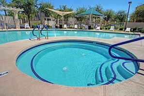 A clear swimming pool with blue tiles, a pool ladder, and lounge chairs around the perimeter. - Across Chicago Cubs (Sloan Park) | Has Shared Pool (Tempe)