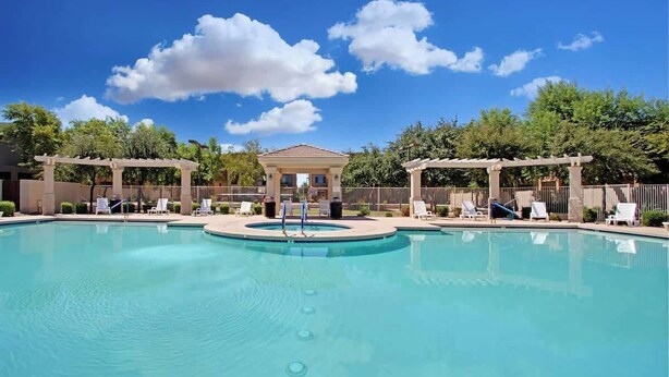 En swimmingpool med solstolar och en pergola.