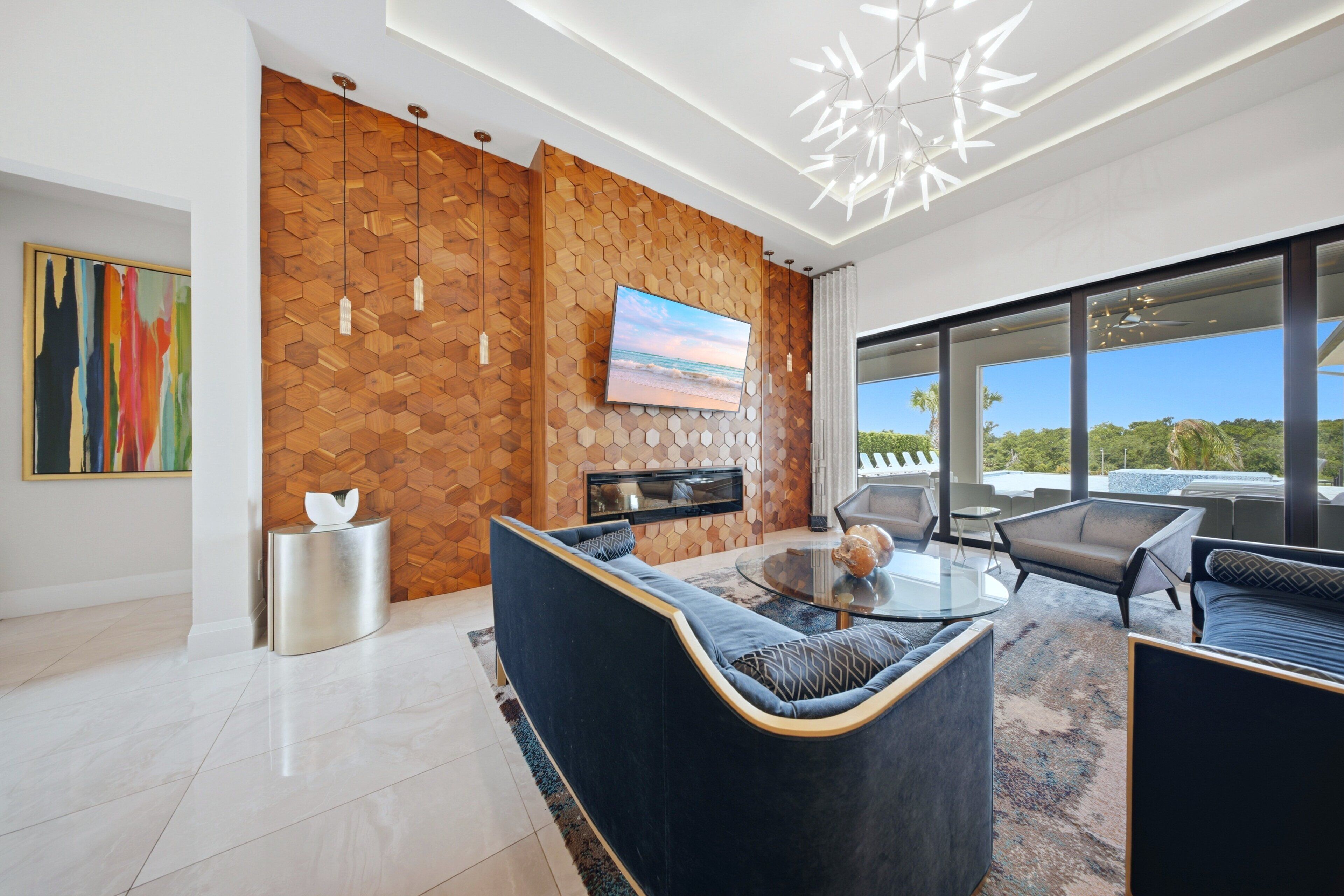 A modern living room with a stone wall, a flat-screen TV, and a glass coffee table.