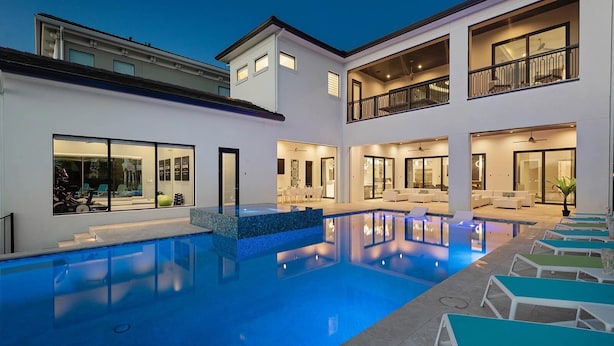 A modern residential property with a swimming pool, multiple balconies, and a well-lit interior.