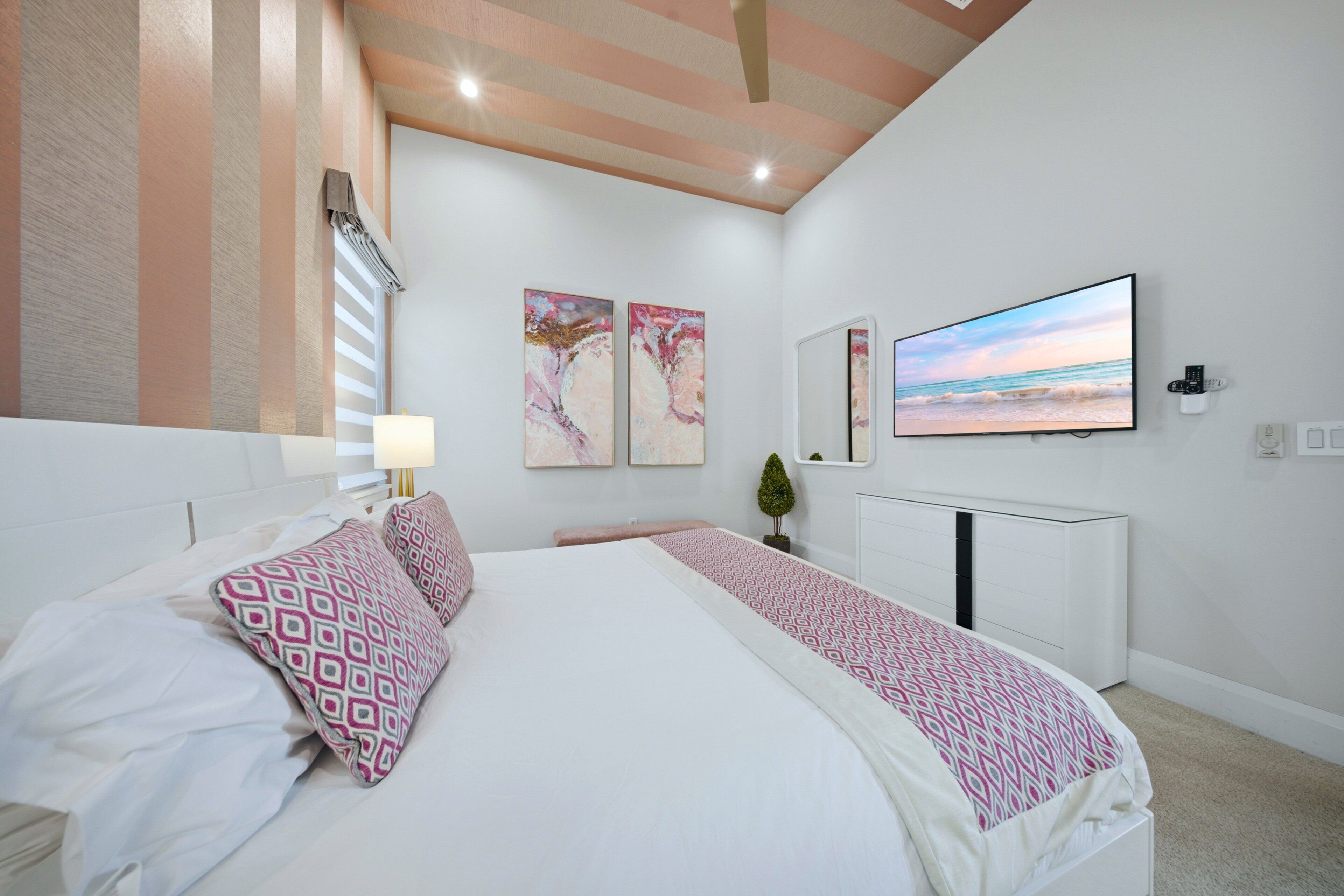 Un dormitorio con cama, televisión y obras de arte en la pared.