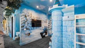 A room with a winter-themed mural, a television, and a castle-like structure.
