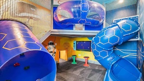 A children's play area with a large blue slide, a climbing wall, and a play structure resembling a space station.