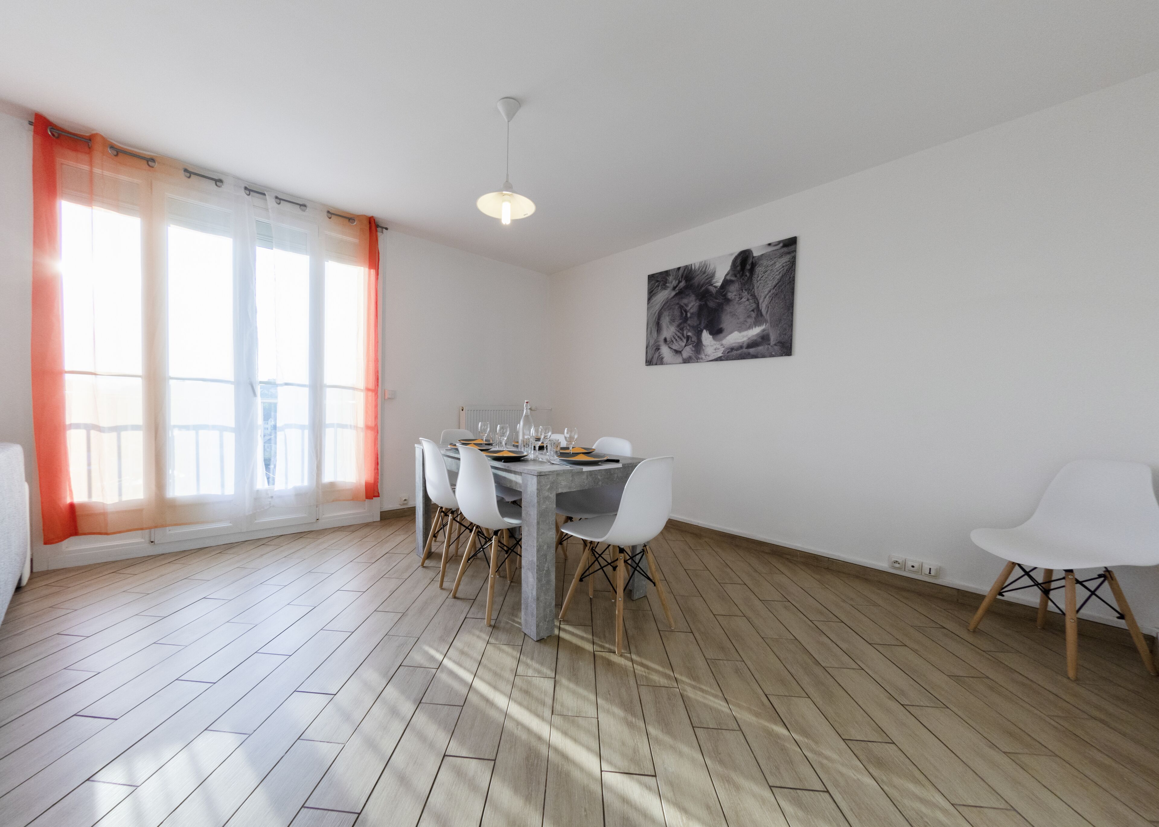 A dining area with a round table, white chairs, and a modern pendant light.