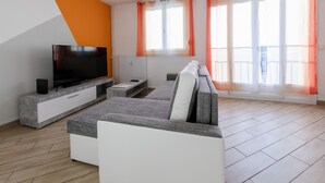 Una sala de estar moderna con un televisor de pantalla plana, un sofá y una mesa de centro.