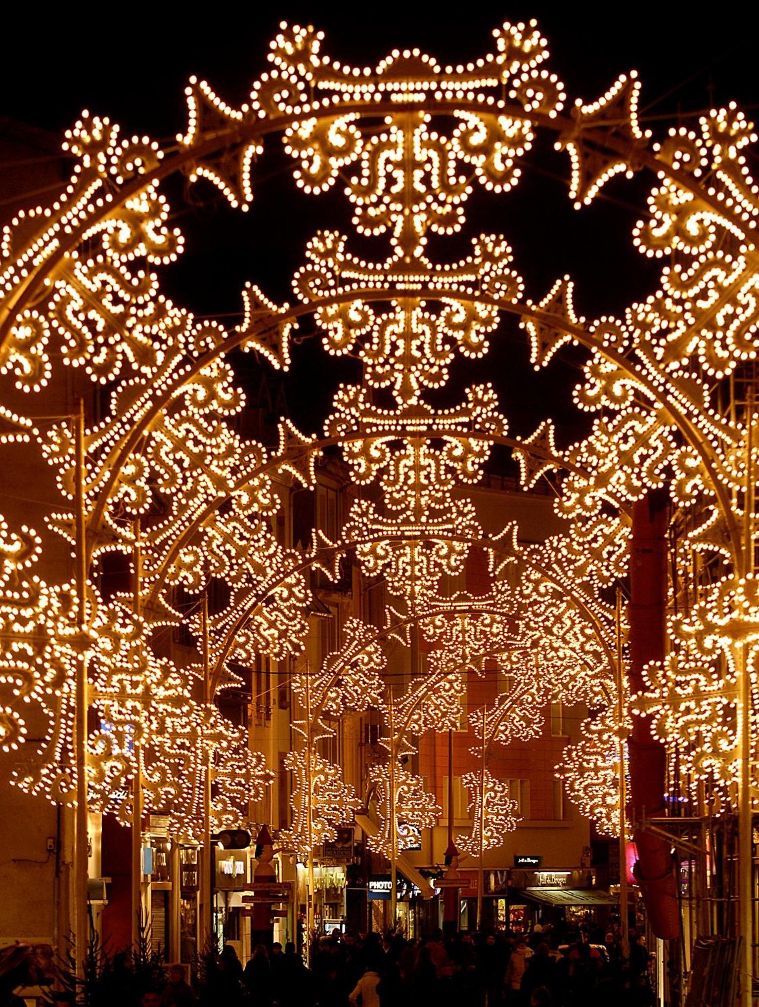 A street lined with ornate, illuminated structures, likely part of a festive event or market.