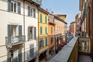 Una calle estrecha flanqueada por edificios de varios pisos, balcones y un cielo despejado.