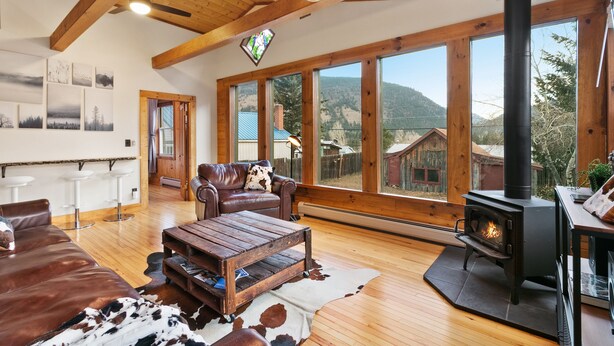 A cozy living room with a fireplace, leather furniture, and large windows offering a mountain view.