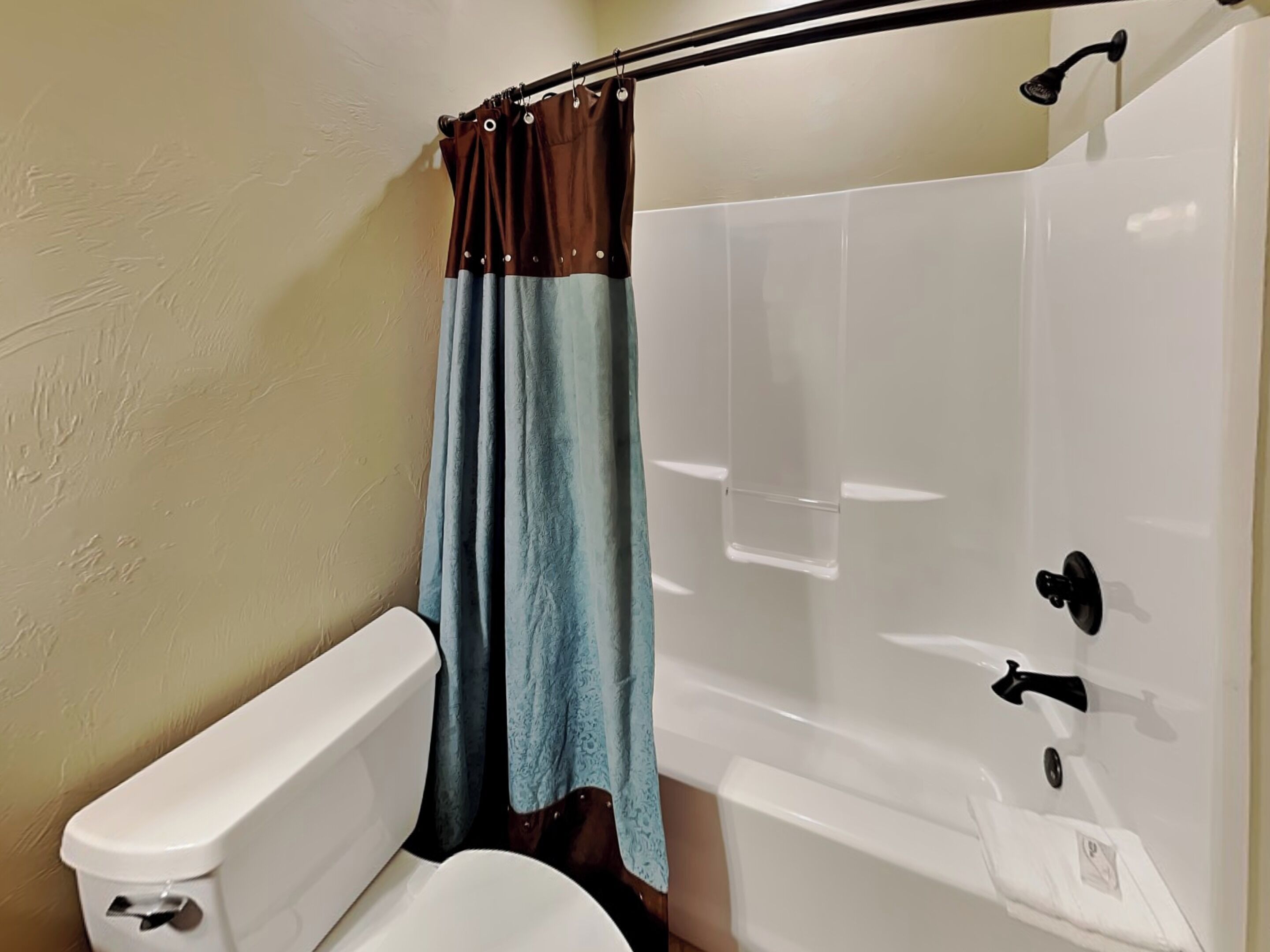 Een badkamer met een wit toilet, een badkuip en een douche.