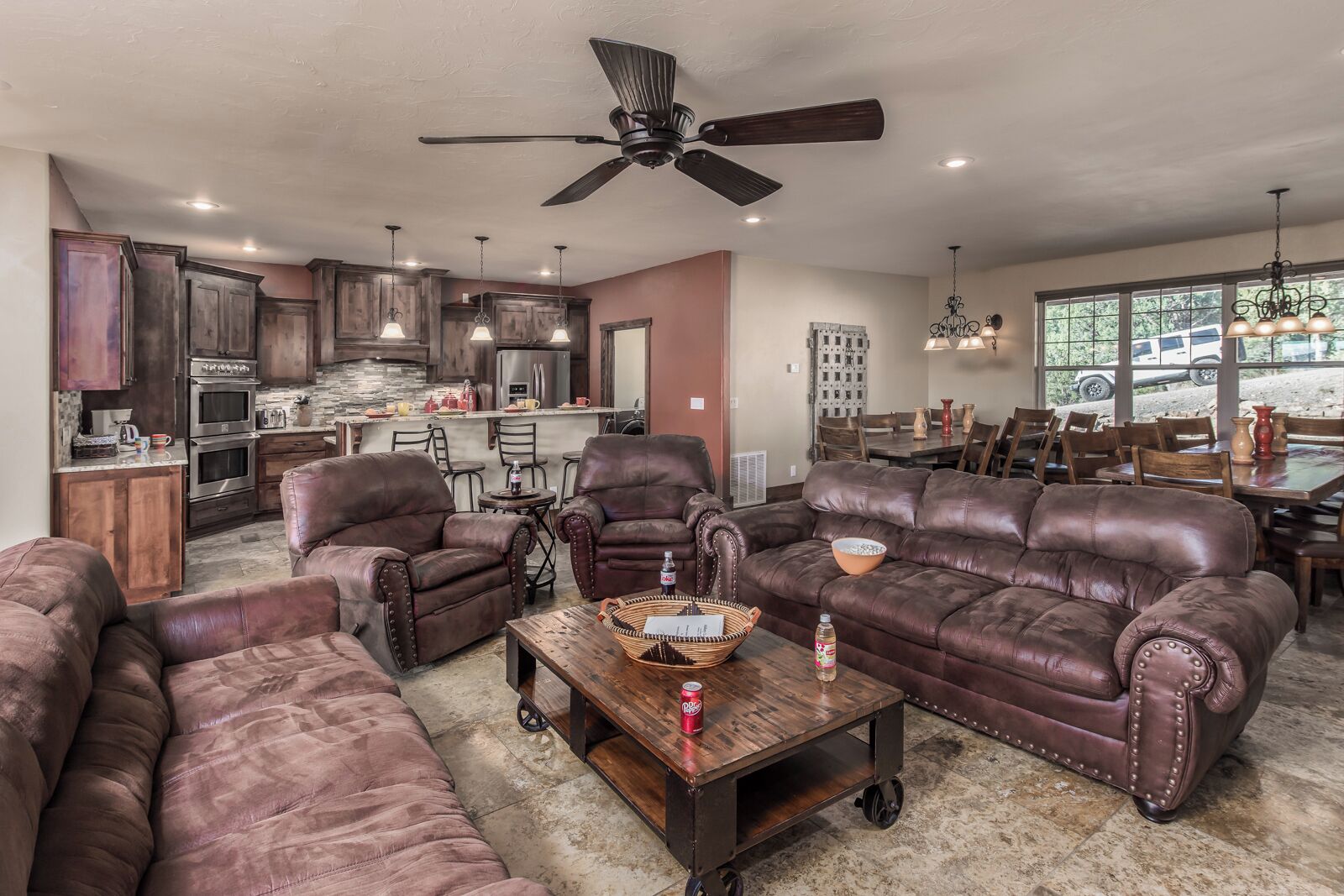 A spacious living room with leather sofas, a coffee table, and a dining area with a large table and chairs.