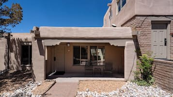 A building with a covered patio area, stone walls, and a door.