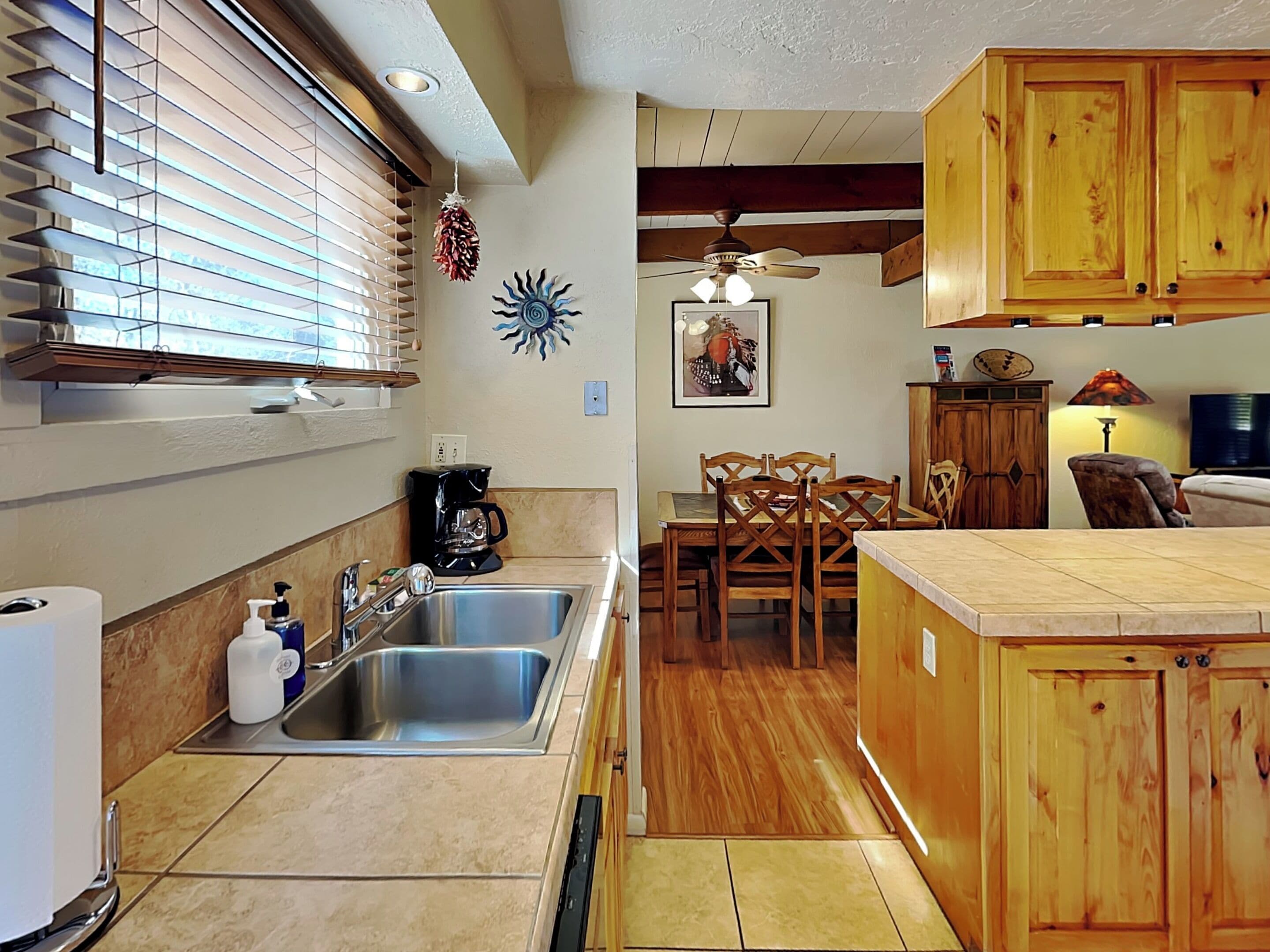 A kitchen with a sink, coffee maker, and wooden cabinets.