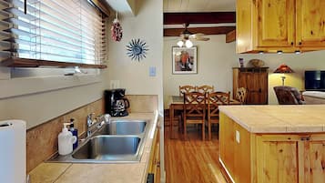A kitchen with a sink, coffee maker, and wooden cabinets.
