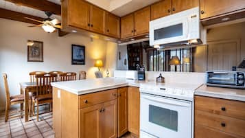 A kitchen with wooden cabinets, a white stove, a microwave, and a toaster.