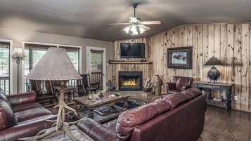 A living room with a fireplace, leather furniture, and a television mounted on the wall.