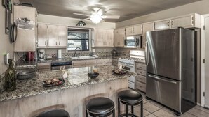 Una cucina moderna con piani di lavoro in granito, elettrodomestici in acciaio inossidabile e mobili in legno.