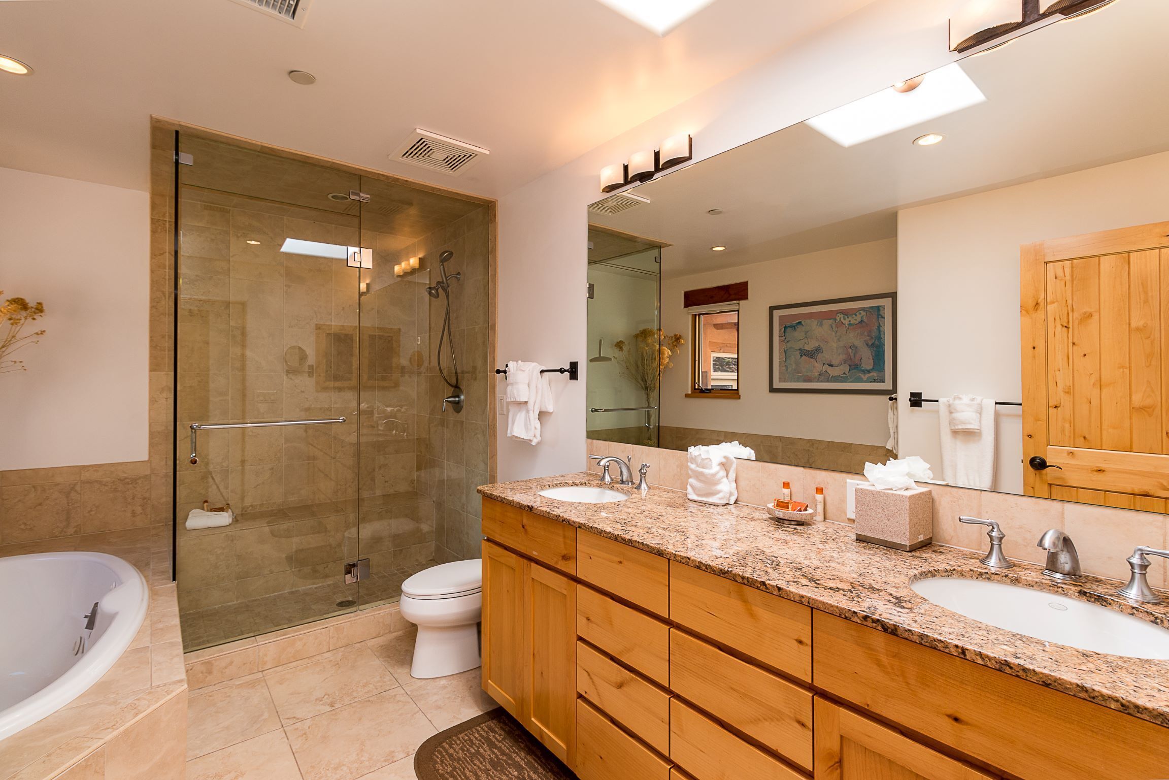 A modern bathroom with a glass-enclosed shower, a large sink with a wooden vanity, and a large mirror.